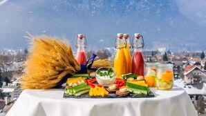 Ein Tisch mit verschiedenen Speisen und Getränken vor einer Berglandschaft.