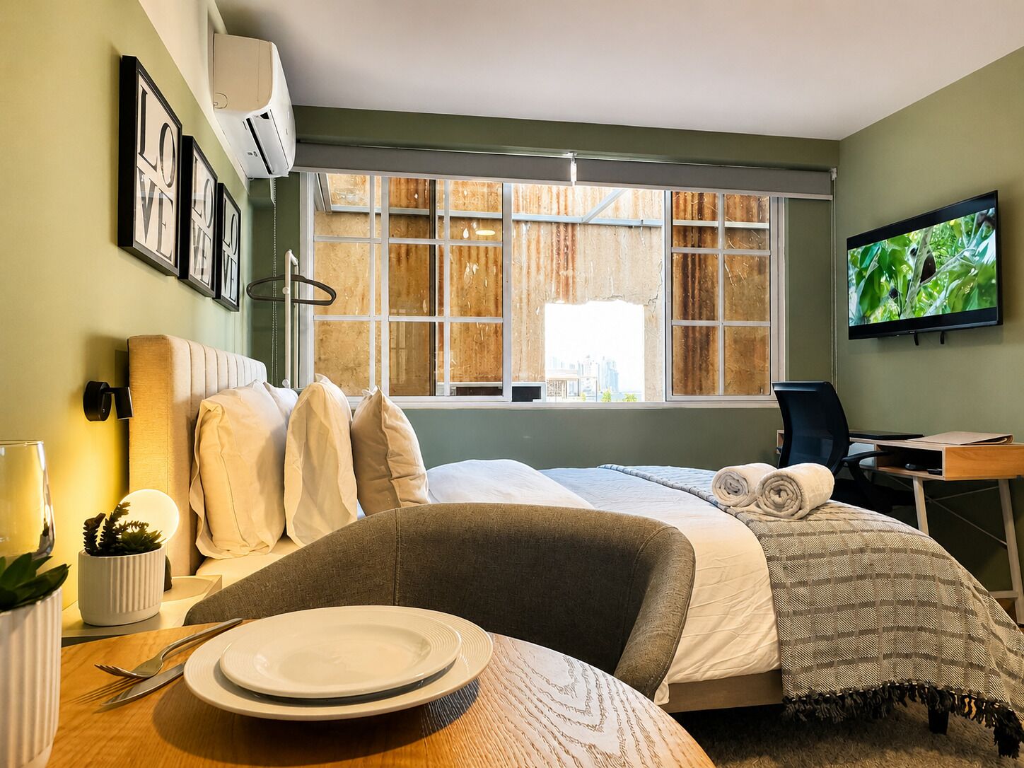 Une chambre d’hôtel avec un lit, un bureau, une télévision et une fenêtre donnant sur la ville.