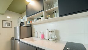 Eine moderne Küche mit integriertem Mikrowellenherd, einer Kaffeemaschine und einer eleganten schwarzen Induktionskochplatte.