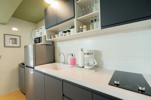 Eine moderne Küche mit integriertem Mikrowellenherd, einer Kaffeemaschine und einer eleganten schwarzen Induktionskochplatte.