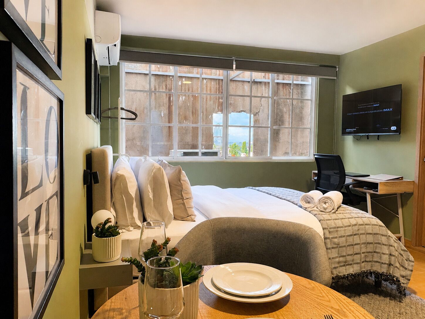 A hotel room with a bed, a desk, a television, and a window with a view.