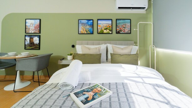 Ein Hotelzimmer mit Bett, Schreibtisch und Stuhl. An der Wand hängen drei gerahmte Bilder.