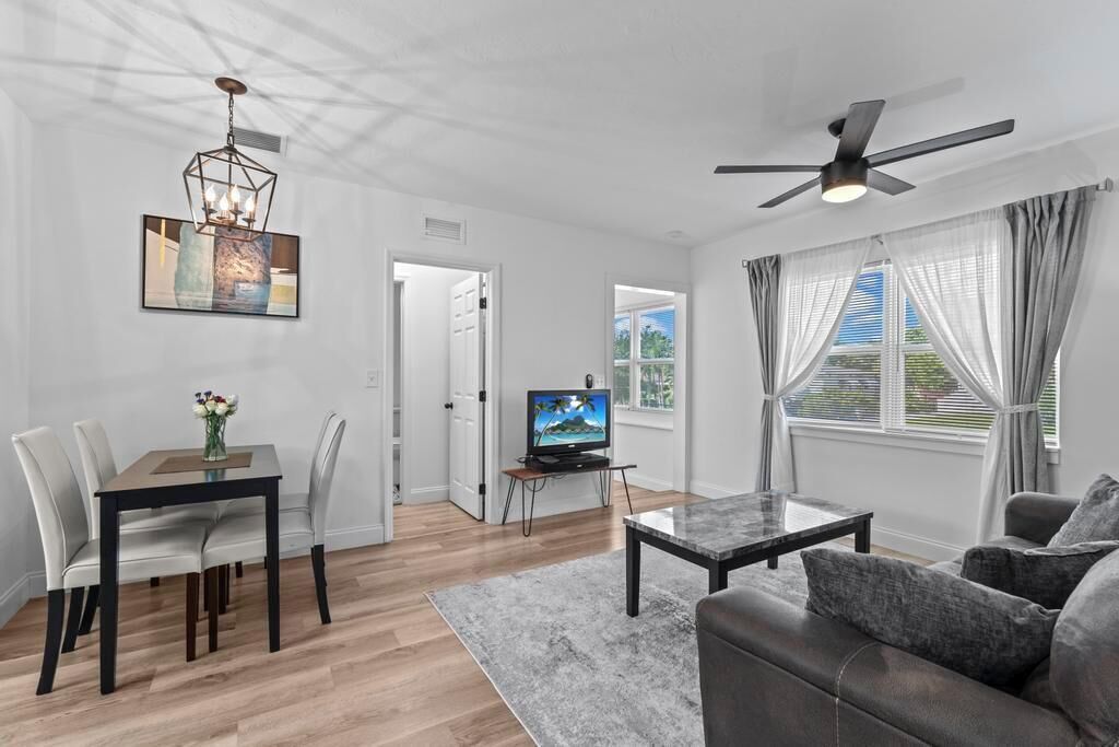 A modern living room with a dining area, a television, and a ceiling fan.