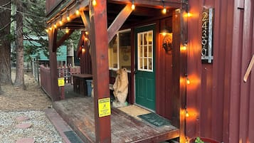 A wooden building with a green door, a number plaque, and a caution sign.
