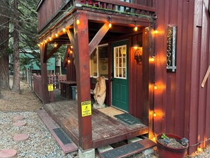 A wooden building with a green door, a number plaque, and a caution sign.