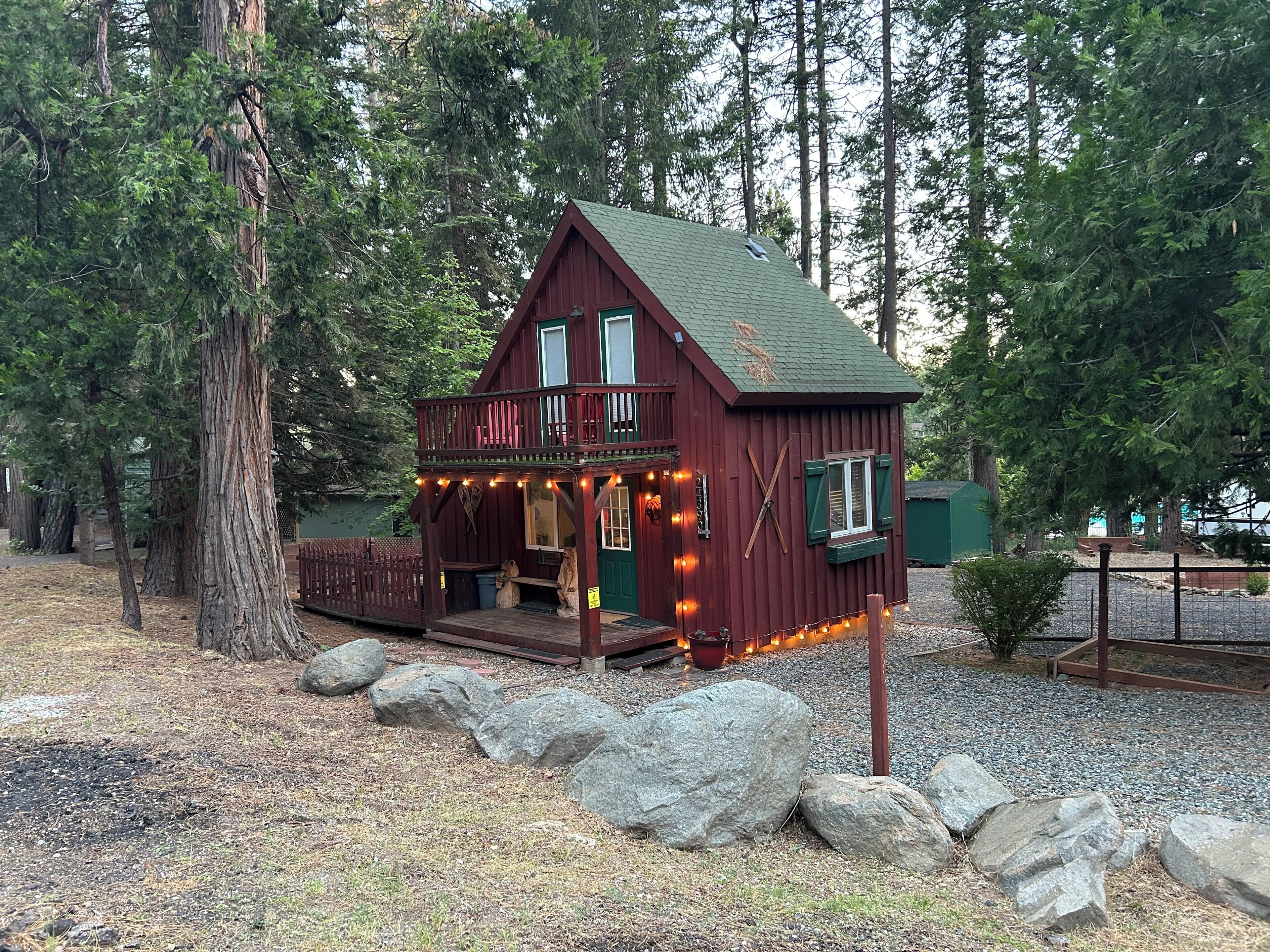 A cabin with a porch, surrounded by trees and rocks.