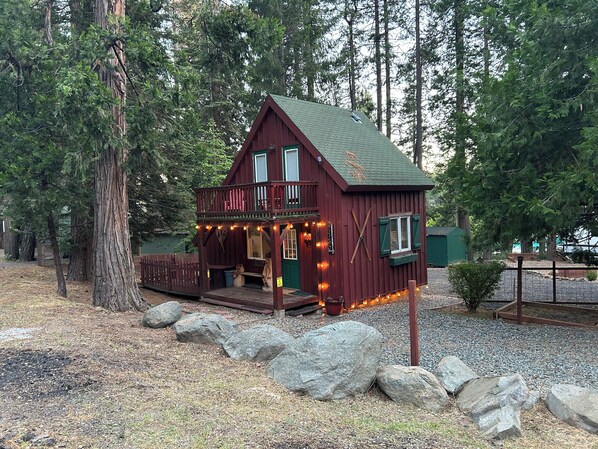 A cabin with a porch, surrounded by trees and rocks.