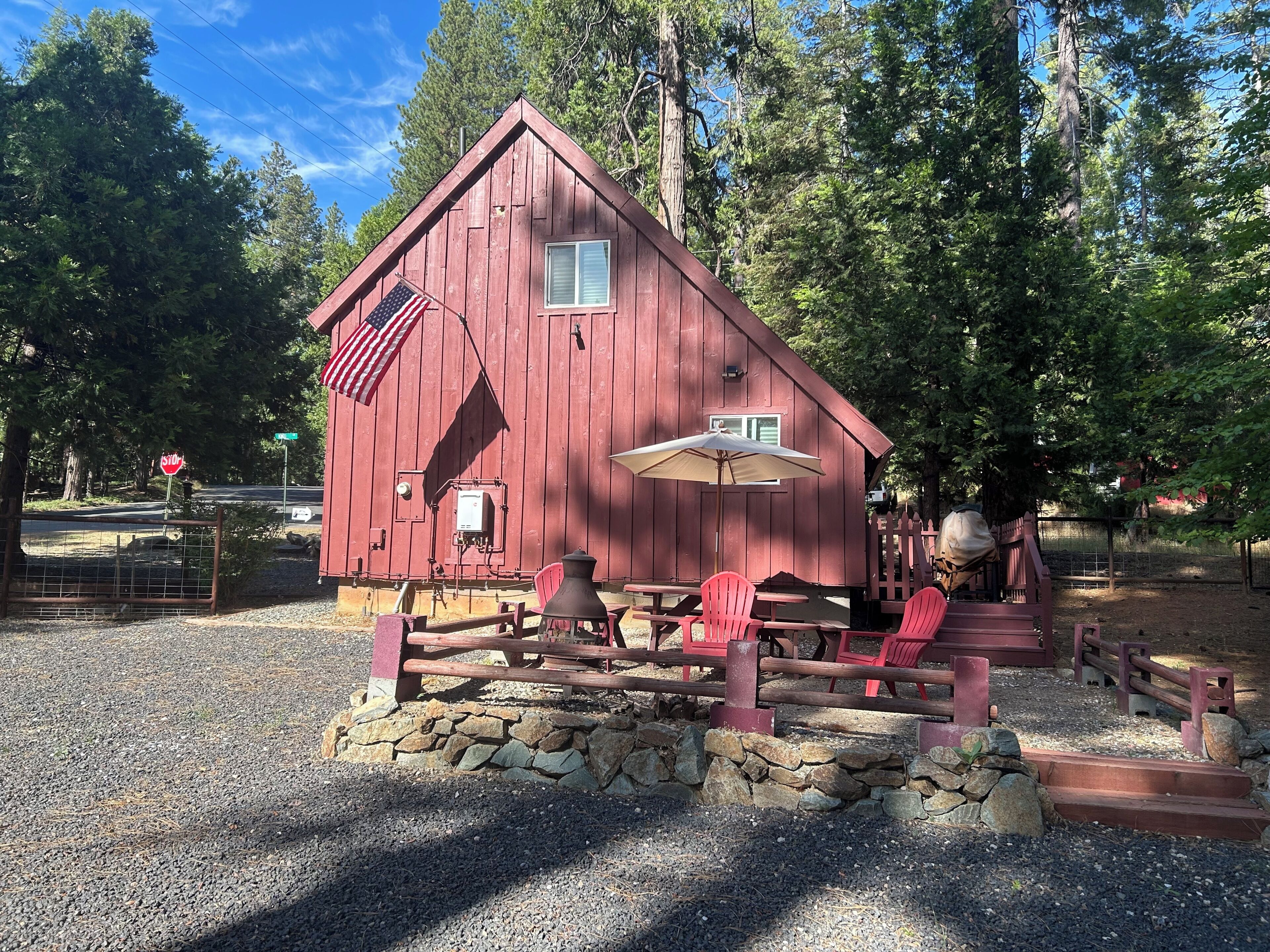 A red wooden building with a stone foundation, a flag, and outdoor seating.