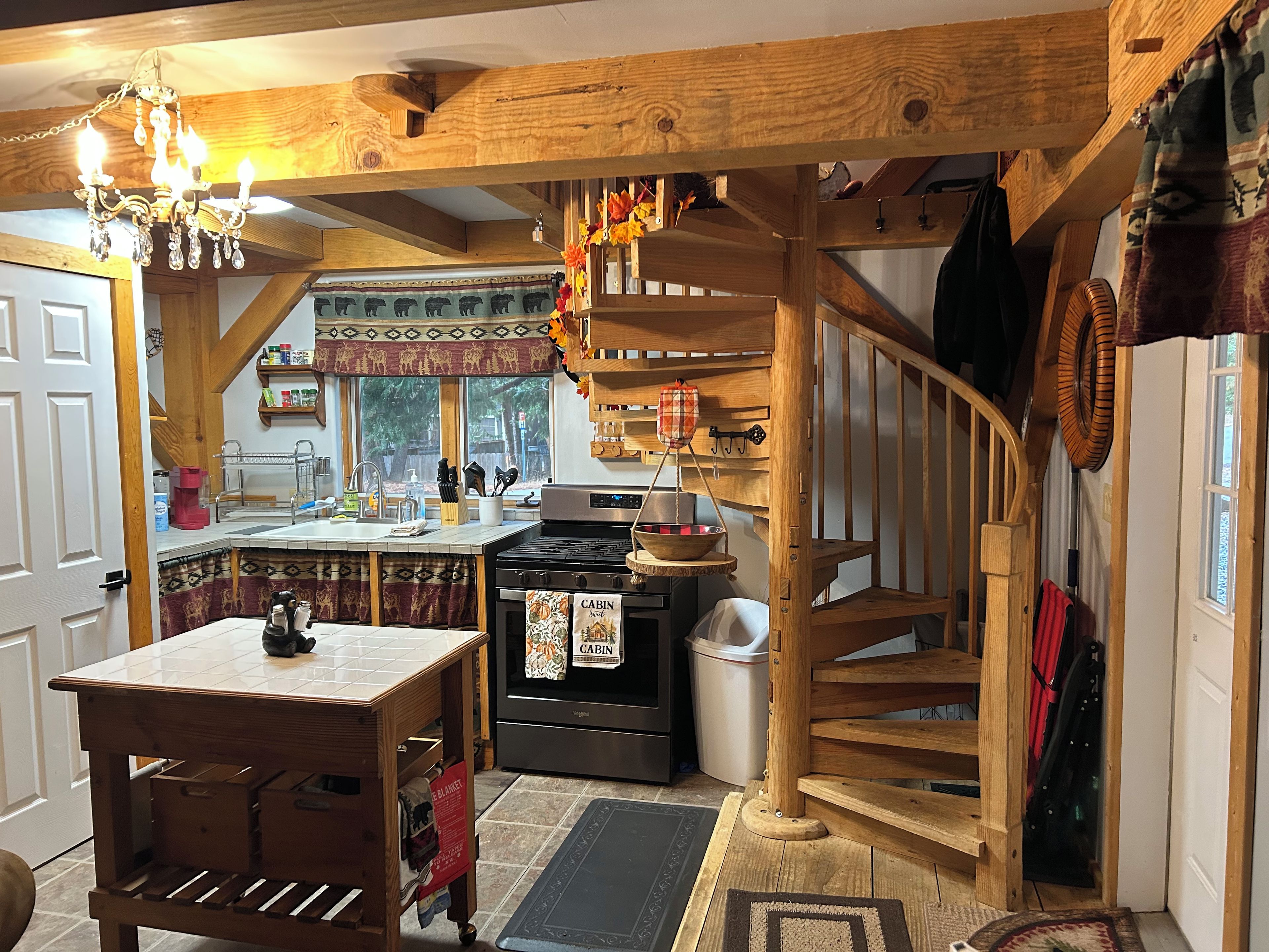 A rustic kitchen with a wooden island, a stove, and a hanging scale.