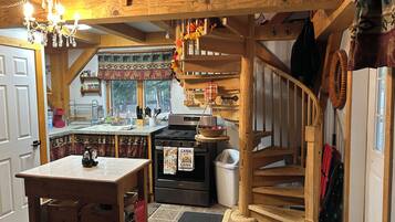A rustic kitchen with a wooden island, a stove, and a hanging scale.