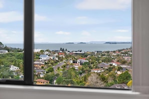 A residential area with houses, trees, and a view of the sea. - Sunny 3BR Retreat Browns Bay Beach Zodiak Stays (Auckland  Central)