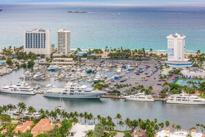 Un port de plaisance où sont amarrés de nombreux yachts, entouré de bâtiments et de palmiers.