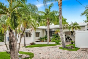 A residential property with a paved driveway, palm trees, and a white building with a covered patio area. - Amazing property next to Las Olas Boulevard (5 min) (Fort Lauderdale)