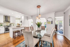A modern kitchen with white cabinetry, a central island, and a dining area with a glass table and cushioned chairs. - Amazing property next to Las Olas Boulevard (5 min) (Fort Lauderdale)