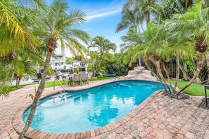 A swimming pool with a stone border, surrounded by palm trees and a patio area with outdoor furniture. - Amazing property next to Las Olas Boulevard (5 min) (Fort Lauderdale)