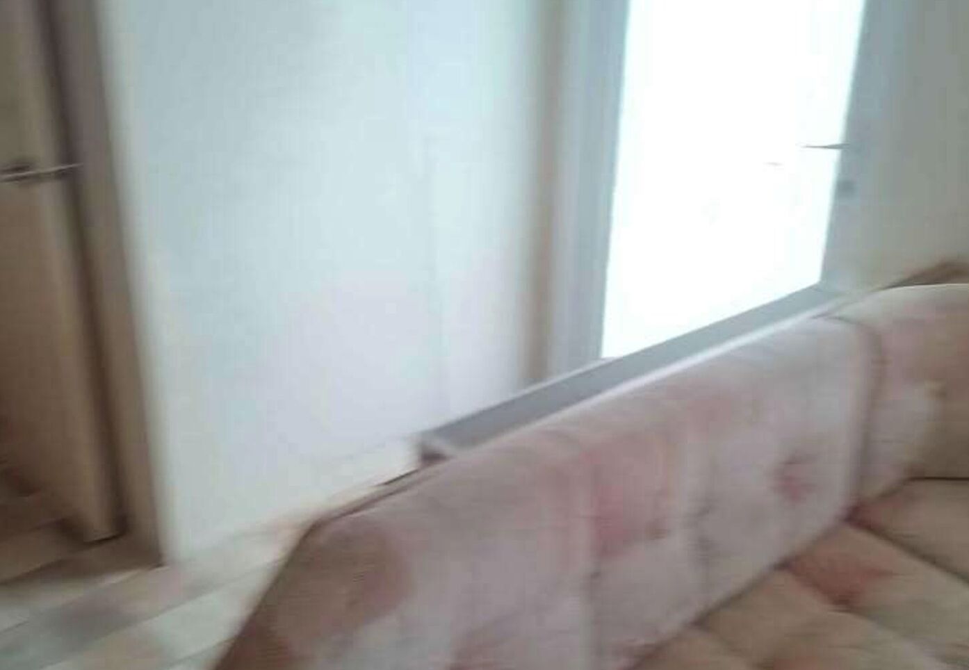 A room with a large window, a sofa, and a door.