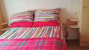 Ein Bett mit karierter Bettdecke und gestreiften Kissen.