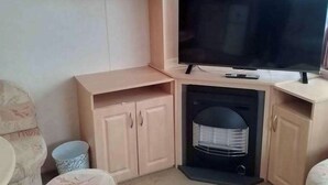 Ein Eckzimmer mit Fernseher, Kamin und Schrank.