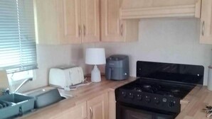 Eine kleine Küche mit Holzschränken, einem Herd, einem Toaster und einer Kaffeemaschine.