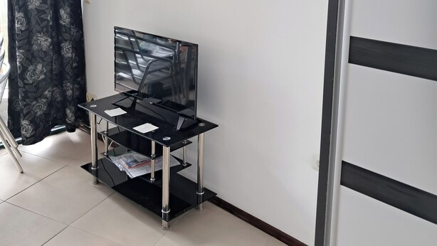Ein Zimmer mit einem Flachbildfernseher auf einem Schrank, einem Bild von einem Boot auf dem Wasser und einer Tür.