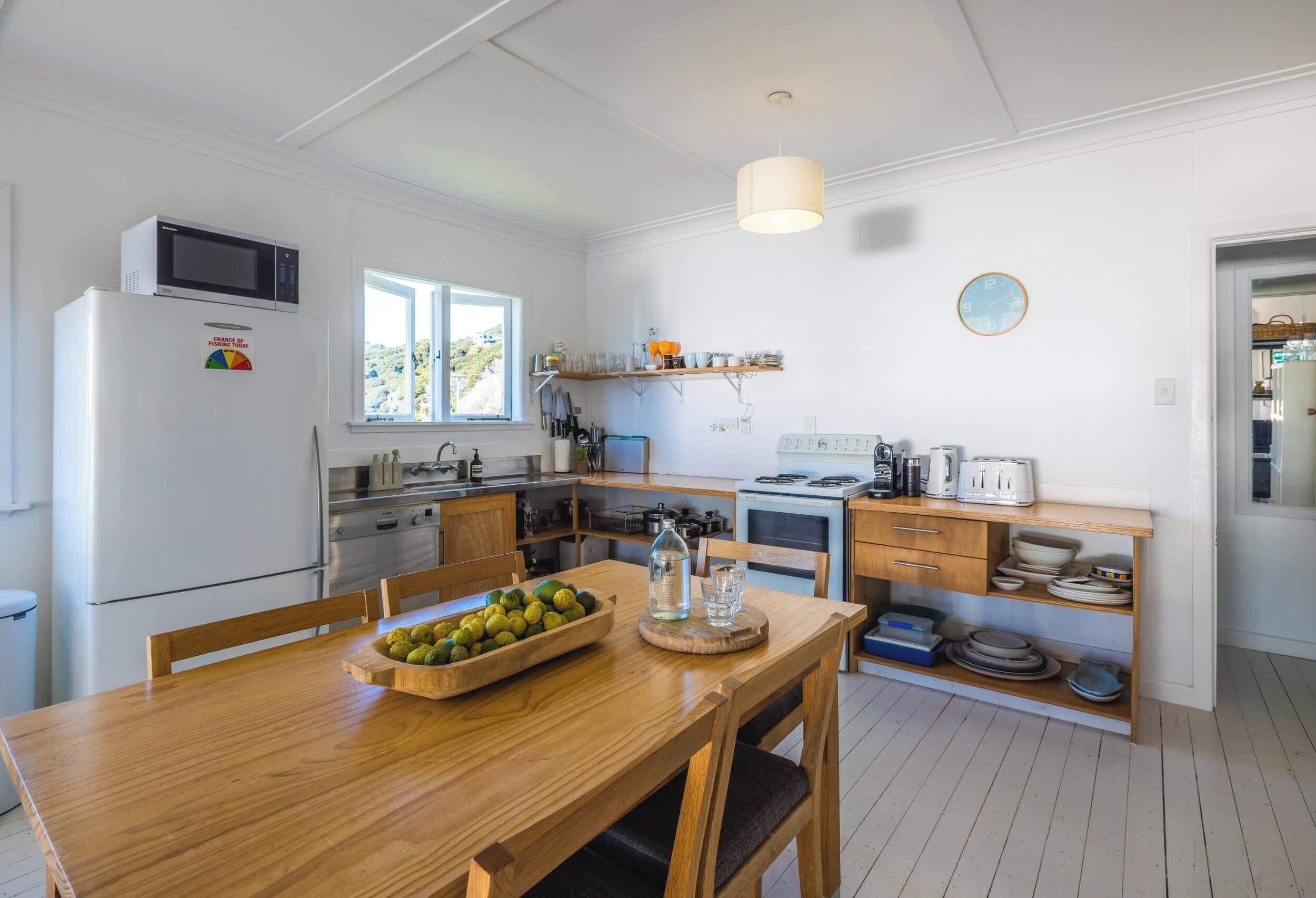 A kitchen with a refrigerator, microwave, wooden table, and various kitchen appliances.