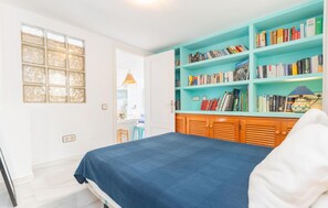 A bedroom with a bed, a bookshelf, and a window.