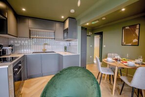 A modern kitchen with grey cabinets, a built-in oven, and a dining area with a round table set for four. - 1 Bedroom Apartments Sleeps 3 - Balcony - Pets Ok (St. Ives)