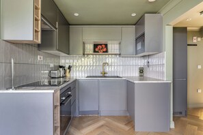 A modern kitchen with grey cabinetry, a stainless steel countertop, and a herringbone wood floor. - 1 Bedroom Apartments Sleeps 3 - Balcony - Pets Ok (St. Ives)
