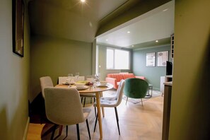 A dining area with a table set for four, a sofa, and a green chair. - 1 Bedroom Apartments Sleeps 3 - Balcony - Pets Ok (St. Ives)