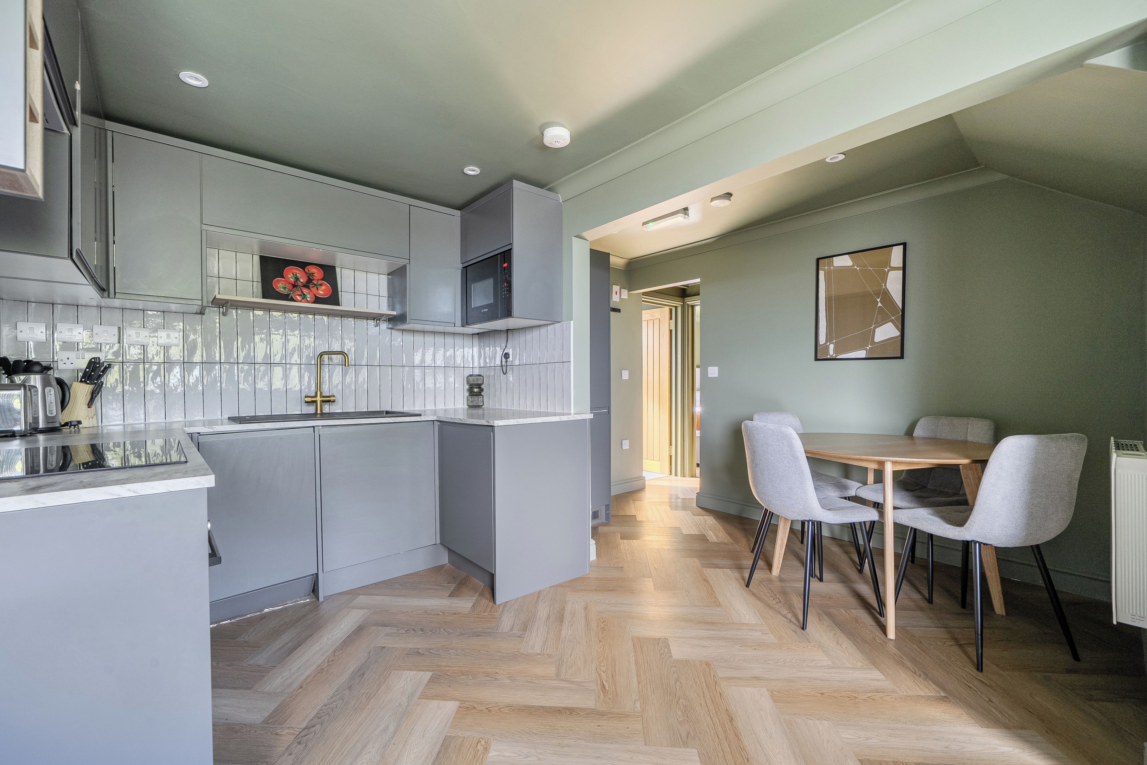 A modern kitchen with grey cabinetry, a microwave, and a tiled backsplash.