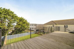 A wooden deck with a metal fence, a grassy area, and a building with a tiled roof. - 1 Bedroom Apartments Sleeps 3 - Balcony - Pets Ok (St. Ives)