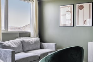 A room with a grey sofa, a green chair, and two abstract art pieces on the wall. - 1 Bedroom Apartments Sleeps 3 - Balcony - Pets Ok (St. Ives)