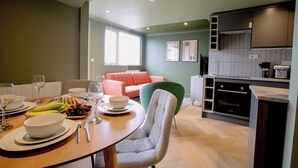 Eine moderne Küche mit Essbereich, einem grünen Sofa und einer Kücheninsel mit Spüle und Herd.