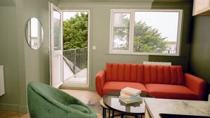 Ein modernes Wohnzimmer mit einem roten Sofa, einem grünen Sessel und einem Glastisch.
