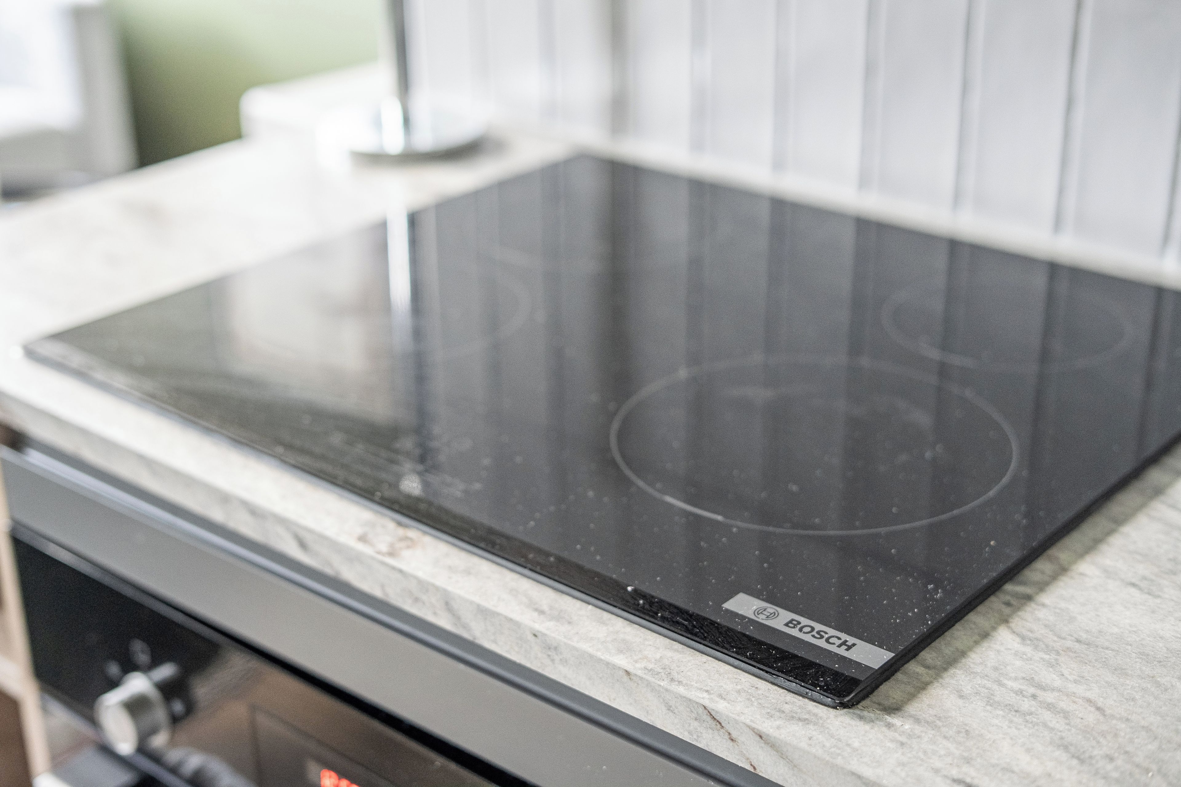 A kitchen with a black Bosch induction cooktop on a marble countertop.