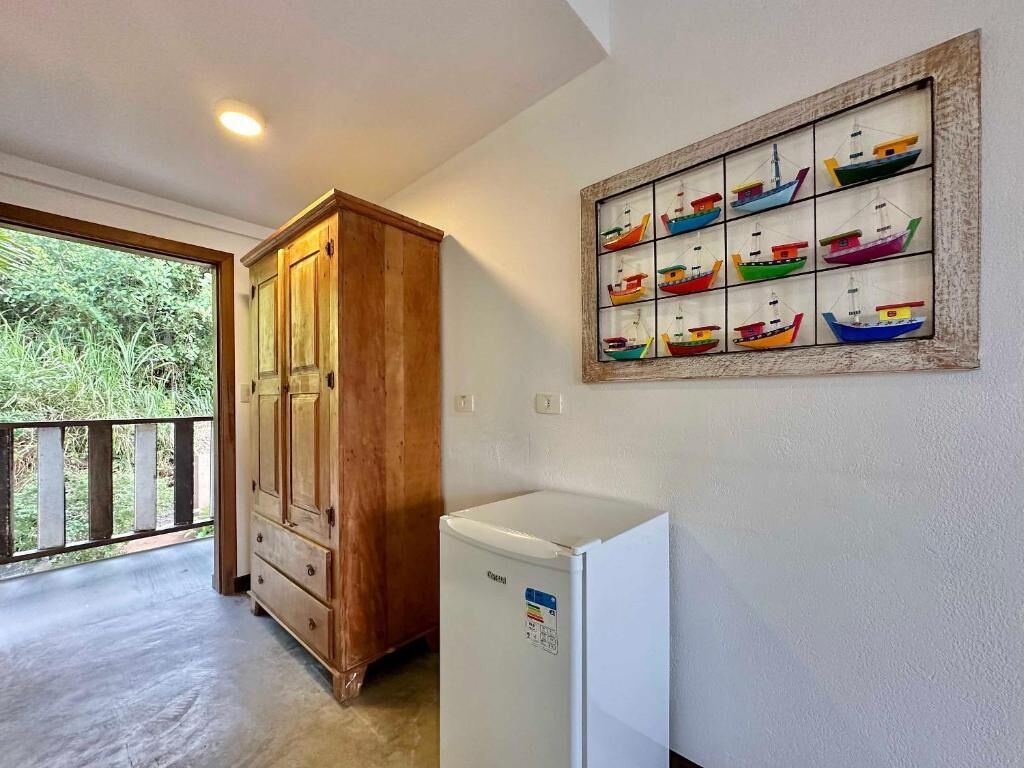 A room with a wooden cabinet, a white refrigerator, and a wall-mounted picture of colorful boats.