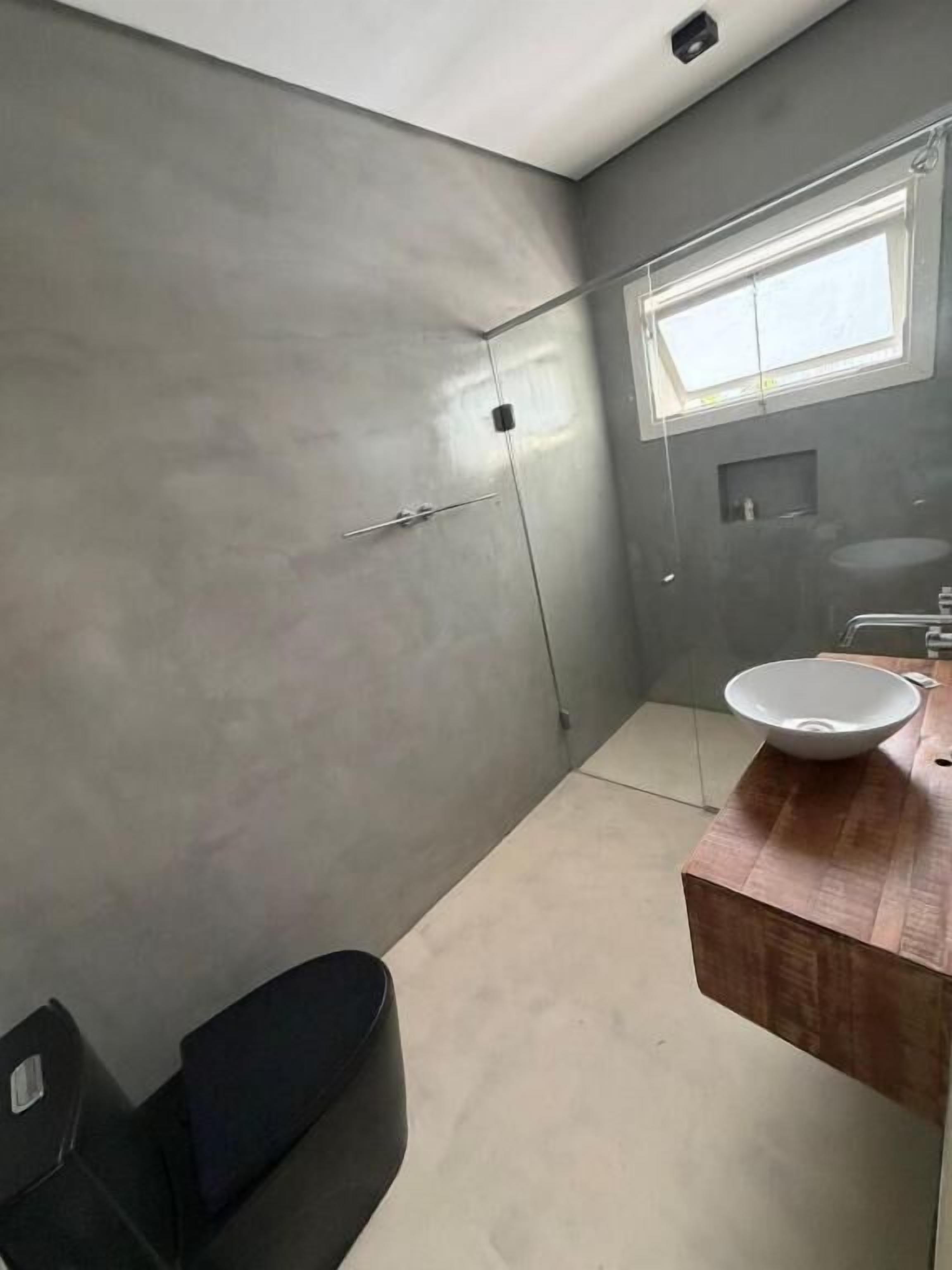 Un baño moderno con un espejo grande, un tocador de madera, un lavamanos blanco y una zona de ducha.