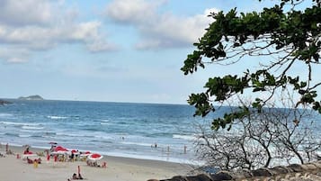 Una playa con gente, sombrillas y vista al océano.