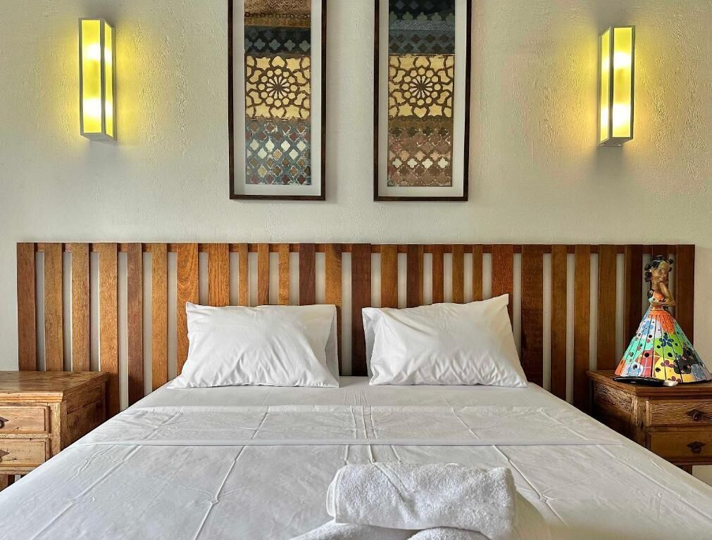 Ein Hotelzimmer mit einem großen Bett, zwei Nachttischen, einem Holzkopfteil und zwei Wandleuchten.