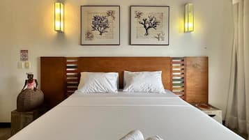 Habitación de hotel con una cama grande, dos luces fijadas a la pared y obras de arte enmarcadas sobre la cama.