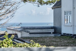 A coastal building with a concrete structure leading to a balcony overlooking the sea. - 1 Bedroom Apartment Sleeps 2 - Pets Welcome (St. Ives)