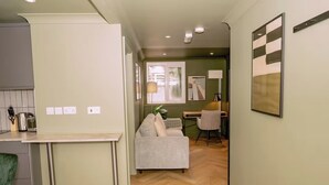 A modern kitchen with a dining area, a sofa, and a desk with a lamp. - 1 Bedroom Apartment Sleeps 2 - Pets Welcome (St. Ives)