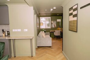 A modern kitchen with a dining area, a sofa, and a desk with a lamp. - 1 Bedroom Apartment Sleeps 2 - Pets Welcome (St. Ives)