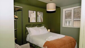A bedroom with a bed, a chair, a bedside table, a lamp, and a window with blinds. - 1 Bedroom Apartment Sleeps 2 - Pets Welcome (St. Ives)