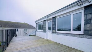 A residential building with a covered wooden deck, a staircase, and large windows. - 1 Bedroom Apartment Sleeps 2 - Pets Welcome (St. Ives)