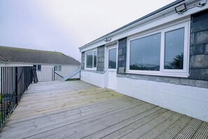 A residential building with a covered wooden deck, a staircase, and large windows. - 1 Bedroom Apartment Sleeps 2 - Pets Welcome (St. Ives)