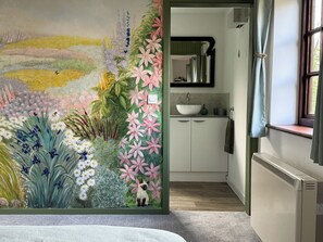 A room with a vibrant floral mural, a window with curtains, a sink, and a radiator.