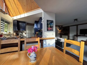 A cozy kitchen with wooden cabinets, a dining table with chairs, and a decorative vase with flowers. - Sleeps 5 with in picturesque Chiddingly (Lewes)