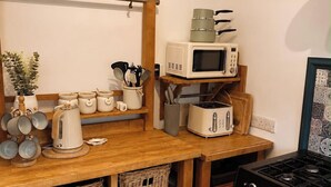 A kitchen with a wooden countertop, a microwave, a toaster, and a stove. - Three-bedroom house in Exmouth, sleeps 6 (Exmouth)