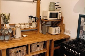 A kitchen with a wooden countertop, a microwave, a toaster, and a stove. - Three-bedroom house in Exmouth, sleeps 6 (Exmouth)
